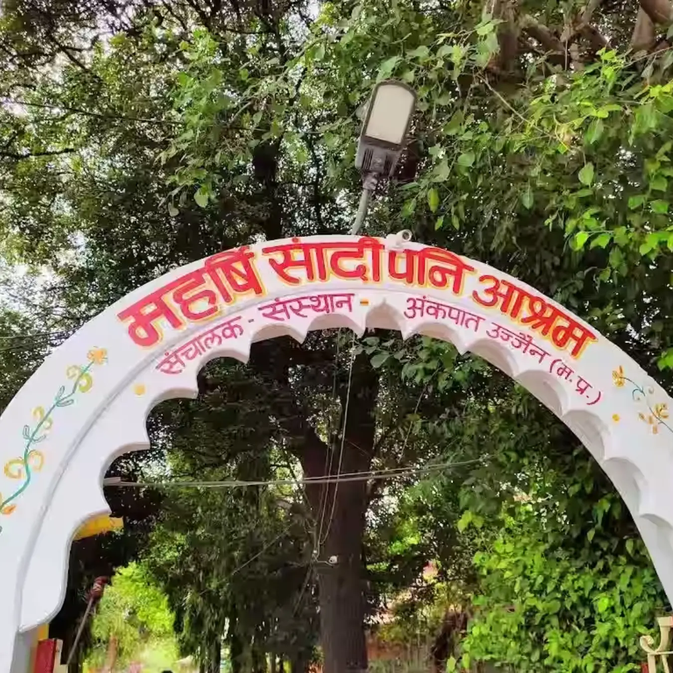 Arched entrance gate of Maharshi Sandipani Ashram surrounded by trees